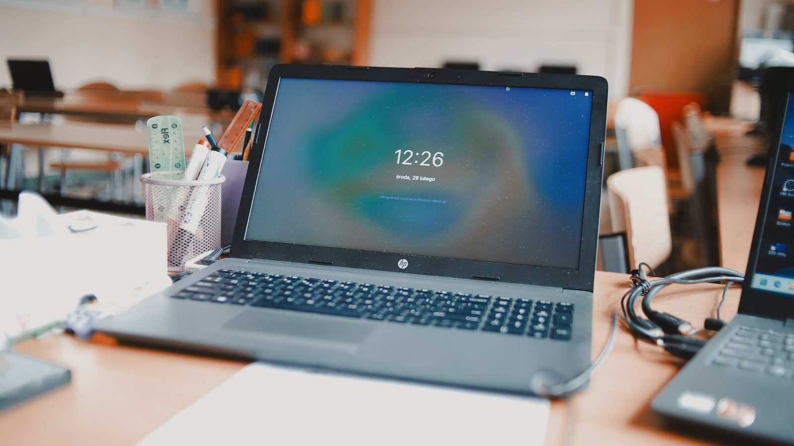 A laptop open on a desk in a bright office, showing its lock screen.